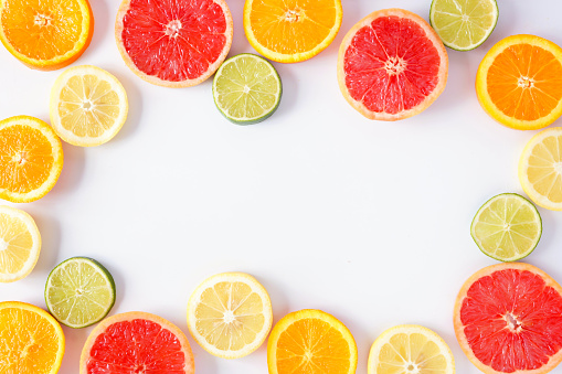 Colorful fruit frame of fresh citrus slices. Top view, flat lay over a white background with copy space.