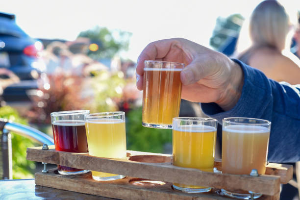 Man sampling beer from flight Man sampling a variety of seasonal craft beer at an outdoor beer garden, hands only craft beer stock pictures, royalty-free photos & images