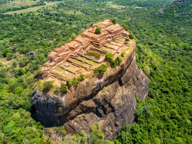 Photo of Aerial view from above of Sigiriya or the Lion Rock, an ancient fortress and a palace with gardens, pools, and terraces atop of granite rock in Dambulla, Sri Lanka. Surrounding jungles and landscape