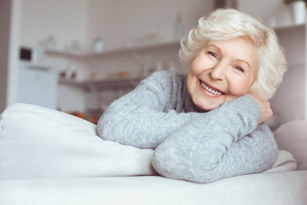 Portrait of handsome grandmother in gray sweater sitting sofa, relaxing stock photo