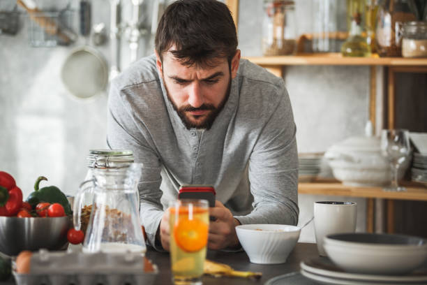 istock Man frowning while looking at smart phone during breakfast at home 1146790732