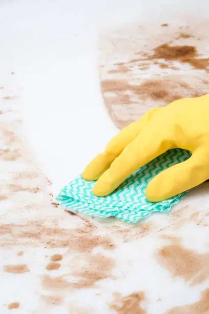 Hand wiping spills on a counter top or floor using a cloth or rag
