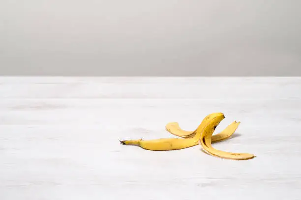 Banana peel on a white wooden surface with copy space