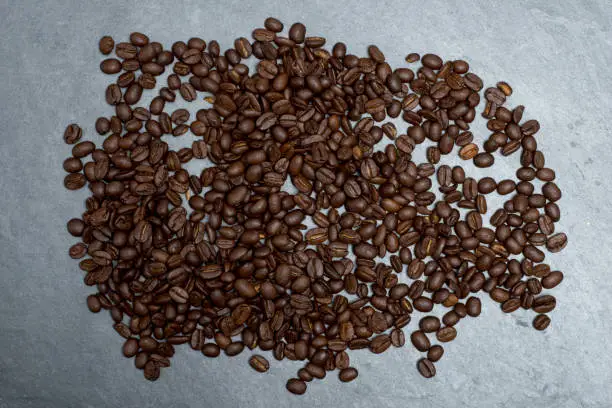 Overhead view of dark, roasted coffee beans on counter top