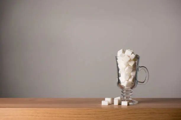 Latte glass overfilled with white sugar glass isolated on a wooden surface, copy space