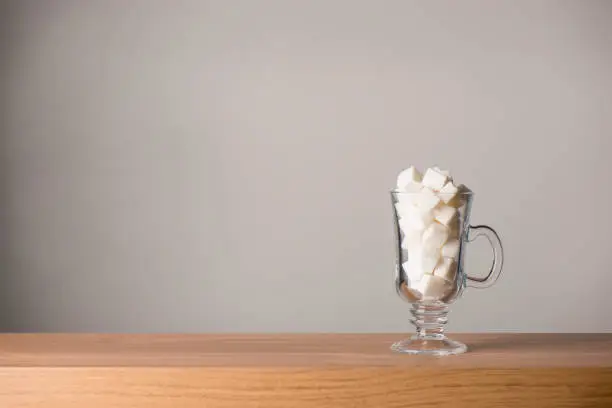 Latte glass filled with white sugar glass isolated on a wooden surface, copy space