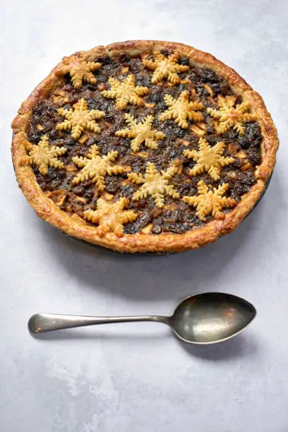 Large whole mince pie and a spoon, traditional British Christmas food