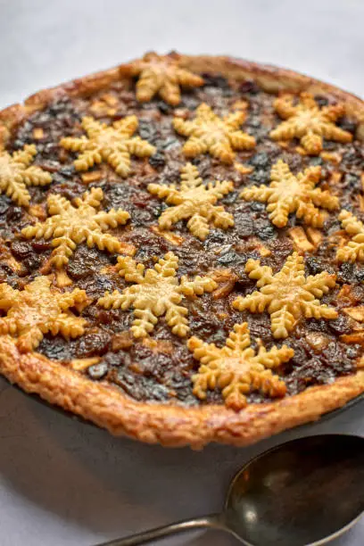 Whole mince pie with snowflake-shaped decoration and a spoon