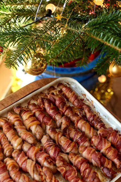 Tray of pigs in blankets beside a Christmas decor