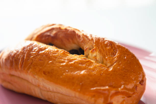 Delicious raisin bun with crispy crust on pink ceramics plate. Looks delicious. Yummy dessert. Fresh from the bakery ready to eat perfect dessert