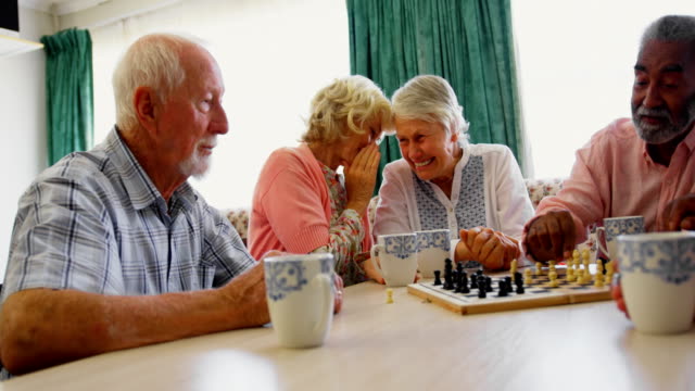 Active mixed-race senior people playing chess game in the nursing home 4k