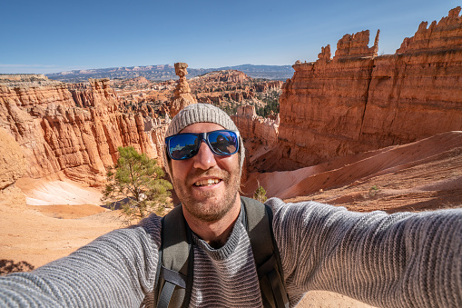Young man takes selfie at Bryce Canyon national park in Utah, United States, people travel explore nature. man hiking and travels