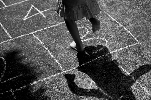 Child playing chalk drawn hopscotch on concrete