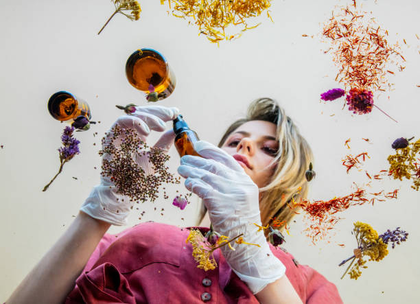 istock Young woman perfumer preparing herbs and flowers for make a perfume. Under table view. 1146824672