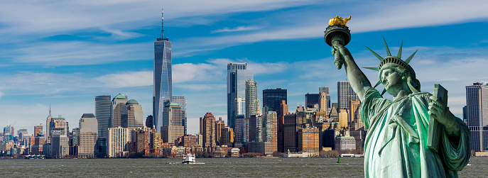 Panorama view of The Statue of Liberty with New York skyscrapers and Manhattan downtown financial district in background, New York skyline at Lower Manhattan, USA.