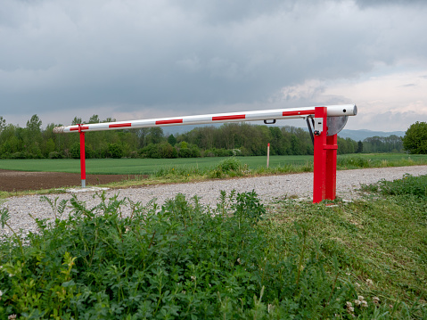Closed Red and White Boom Gate or Boom Barrier on a Gravel Path in the Countryside