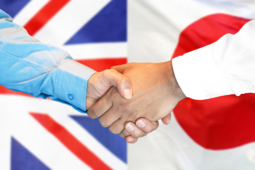 Business handshake on the background of two flags. Men handshake on the background of the United Kingdom and Japan flag. Support concept