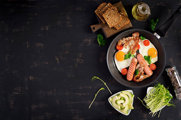 istock English breakfast - fried egg, tomatoes, sausage and bacon. Top view 1146833133