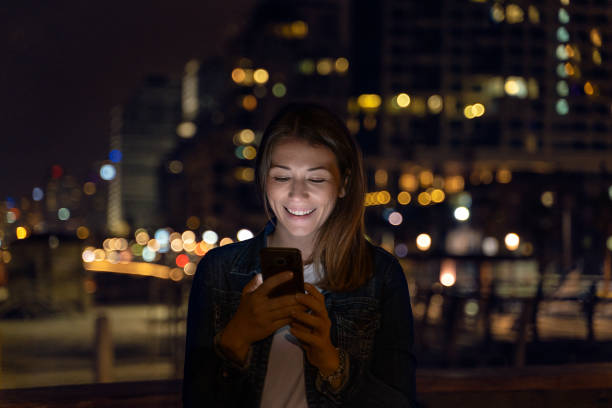 istock young woman using her smartphone during the night. city light as background 1146834127