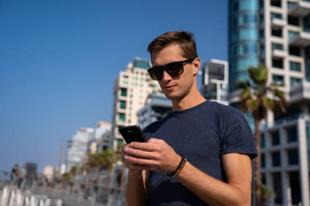 istock young man using the phone. City Skyline In Background 1146834354