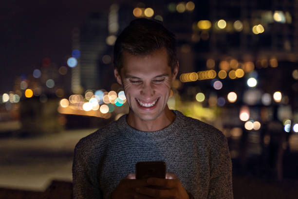 istock young man using her smartphone during the night. city light as background 1146834477