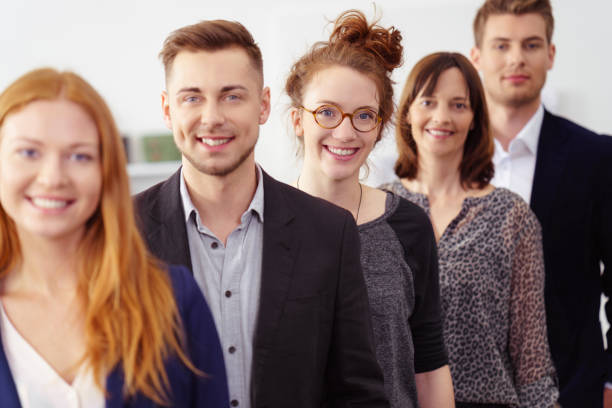 Smiling group of young professionals in office Smiling group of young professionals in office wearing business attire while standing in a line business relationship photos stock pictures, royalty-free photos & images