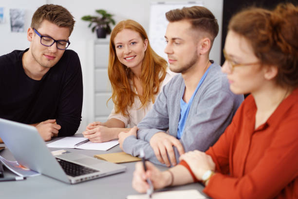 istock Smiling woman with coworkers around laptop at work 1146846853