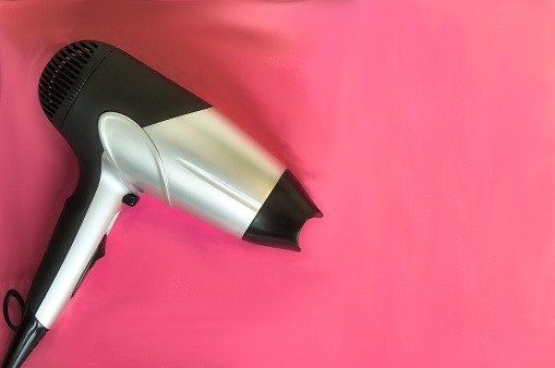 black and silver electric hair dryer on pink background (blow dryer)