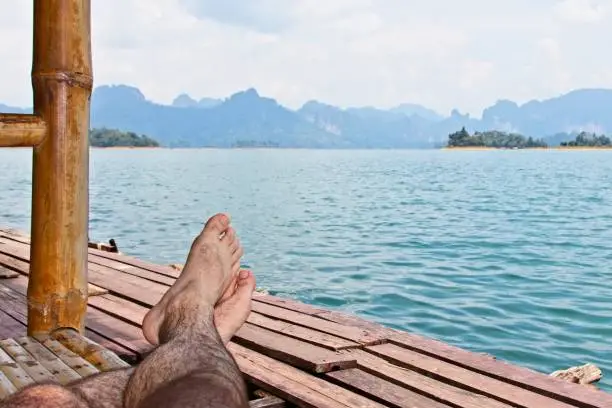 Photo of A Caucasian man enjoying the view from a raft house on the Khao Sok National park lake in Thailand.  Tourism background image.