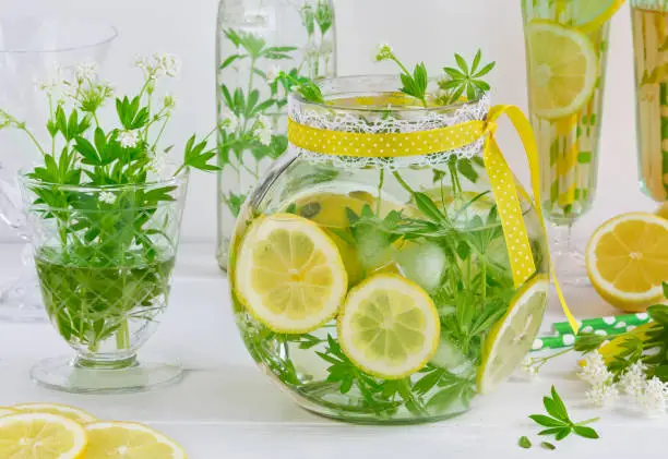 Refreshing drink blooming woodruff with lemon and ice cubes in glass jar