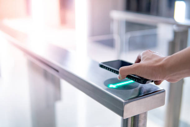 main mâle utilisant le smartphone pour ouvrir la machine automatique de barrière dans le bâtiment de bureau - door tickets photos et images de collection