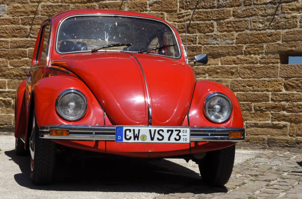 Bisingen, Germany - June 06, 2014: A red model of Volkswagen Type 1 Beetle parked in front of a sandstone wall.
