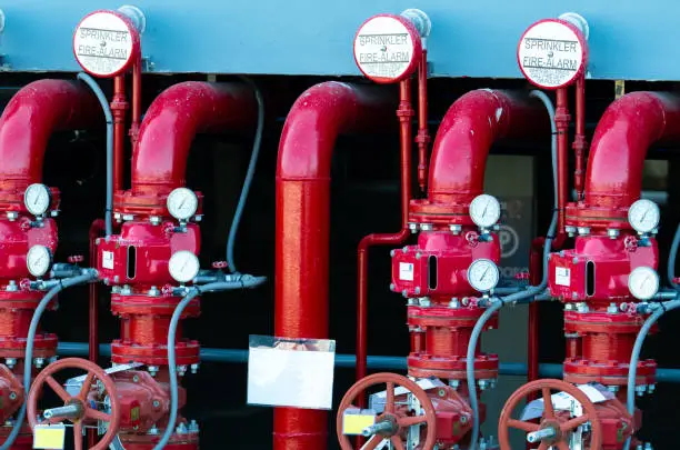 Photo of Main supply water piping in the fire extinguishing system. Fire sprinkler system with red pipes. Fire suppression. Manual valve of Fire extinguisher system.