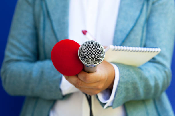 istock Female journalist at news conference, writing notes, holding microphone 1146883365