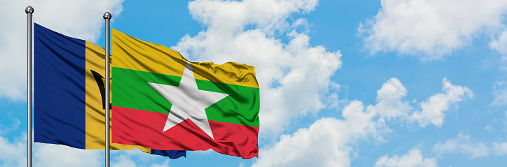 Barbados and Myanmar flag waving in the wind against white cloudy blue sky together. Diplomacy concept, international relations.