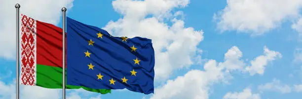 Belarus and European Union flag waving in the wind against white cloudy blue sky together. Diplomacy concept, international relations.