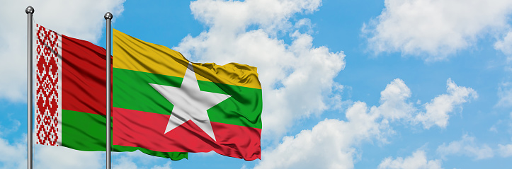 Belarus and Myanmar flag waving in the wind against white cloudy blue sky together. Diplomacy concept, international relations.