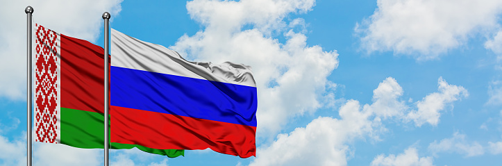 Bielorrusia y Rusia bandera ondeando en el viento contra el cielo azul nublado blanco juntos. Concepto de diplomacia, relaciones internacionales. photo