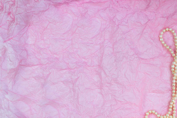 istock Pearl necklace on pink wrinkled paper texture background 1146887509