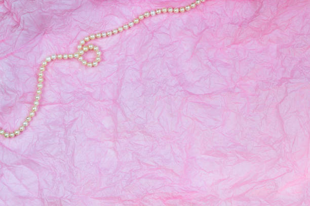 istock Pearl necklace on pink wrinkled paper texture background 1146887519