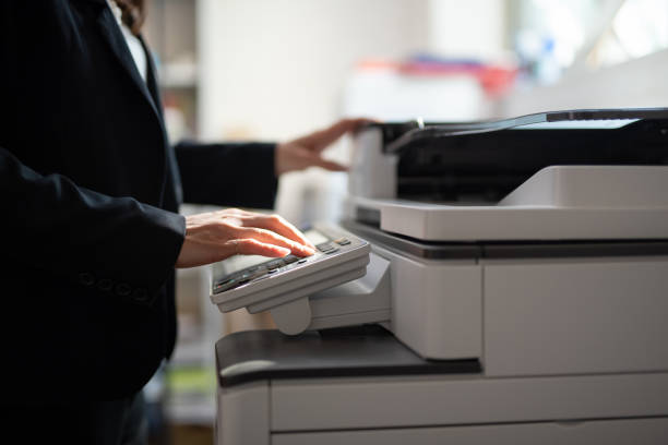 бизнесвумен делает копии с копировальной машиной в офисе - copy area стоковые фото и изображения