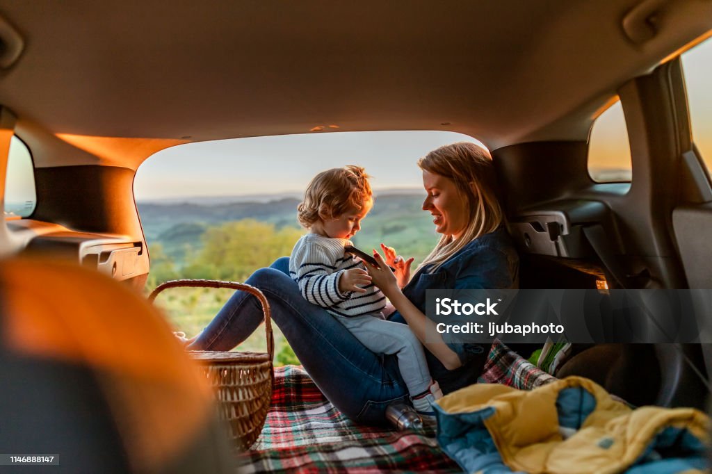Madre e hijo con almohadilla durante el viaje en coche por la noche - Foto de stock de Coche libre de derechos