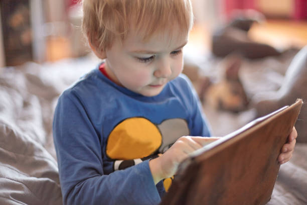 istock Little caucasian baby boy sits on the sofa using a tablet, touching screen. 1146889845