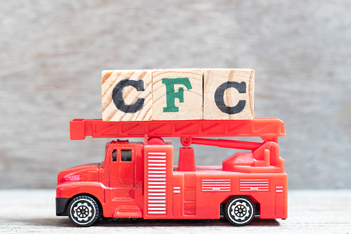 Red fire truck hold letter block in word CFC (abbreviation of Chlorofluorocarbon) on wood background