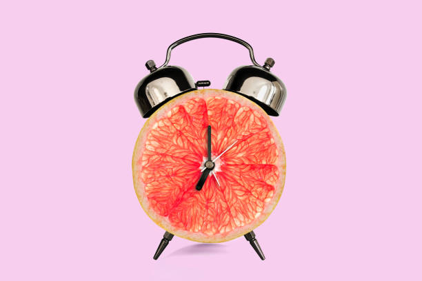 istock Grapefruit slice on alarm clock, pink pastel background. fruit and vitamins diet at breakfast nutrition concept 1146891684