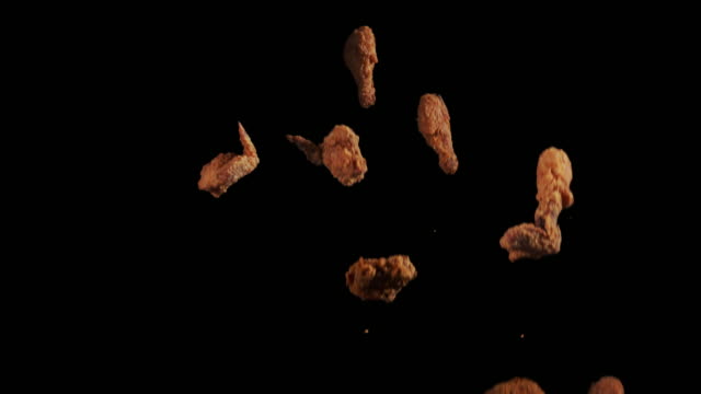 Slow motion of Fried chicken drumstick, chest and wing part toss and thrown on black background