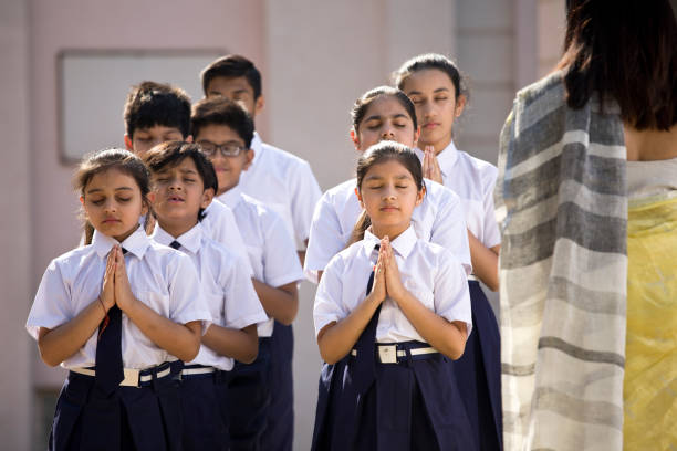 istock Teacher with students praying in school campus 1146896027
