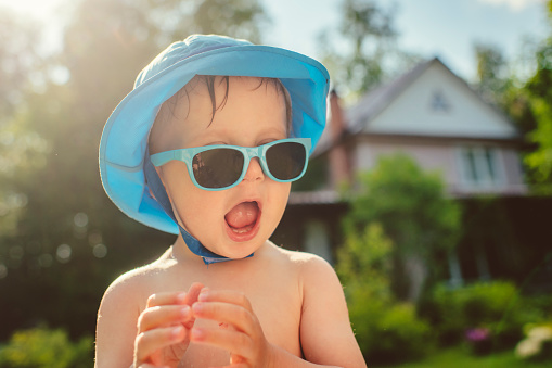 Cute child in sunglasses in summer at back yard