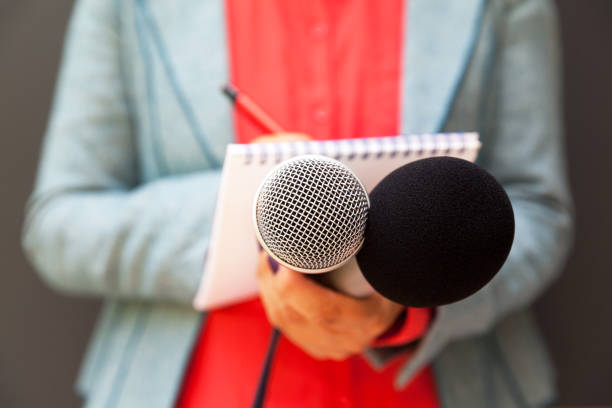 istock Female reporter at press conference, writing notes, holding microphone 1146900927