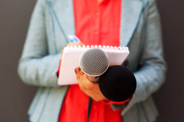 istock Female journalist at press conference, writing notes, holding microphone 1146901764